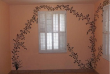 wall with a lit windowpane and painted plant that spirals toward the window